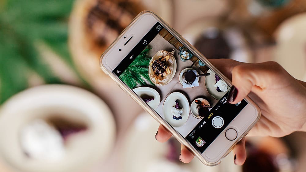 Person taking photos of the food they sell in a restaurant for online sales and ecommerce via their Shopify site.