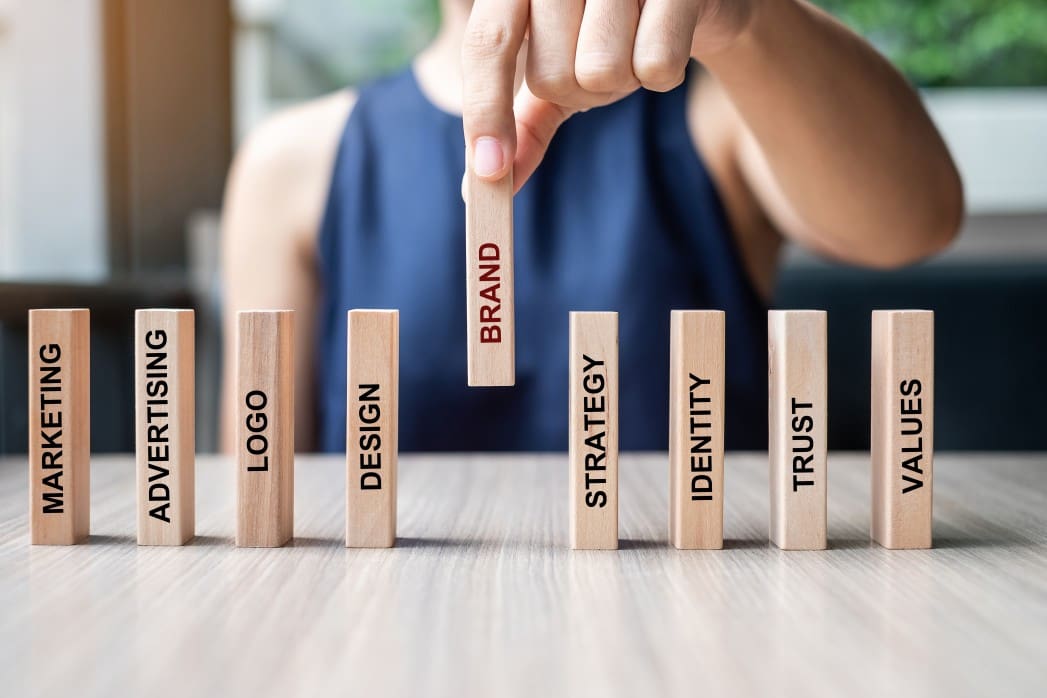 businesswoman-hand-placing-or-pulling-wooden-dominoes-with-brand-text-and-marketing-advertising-logo_t20_YwXeLX