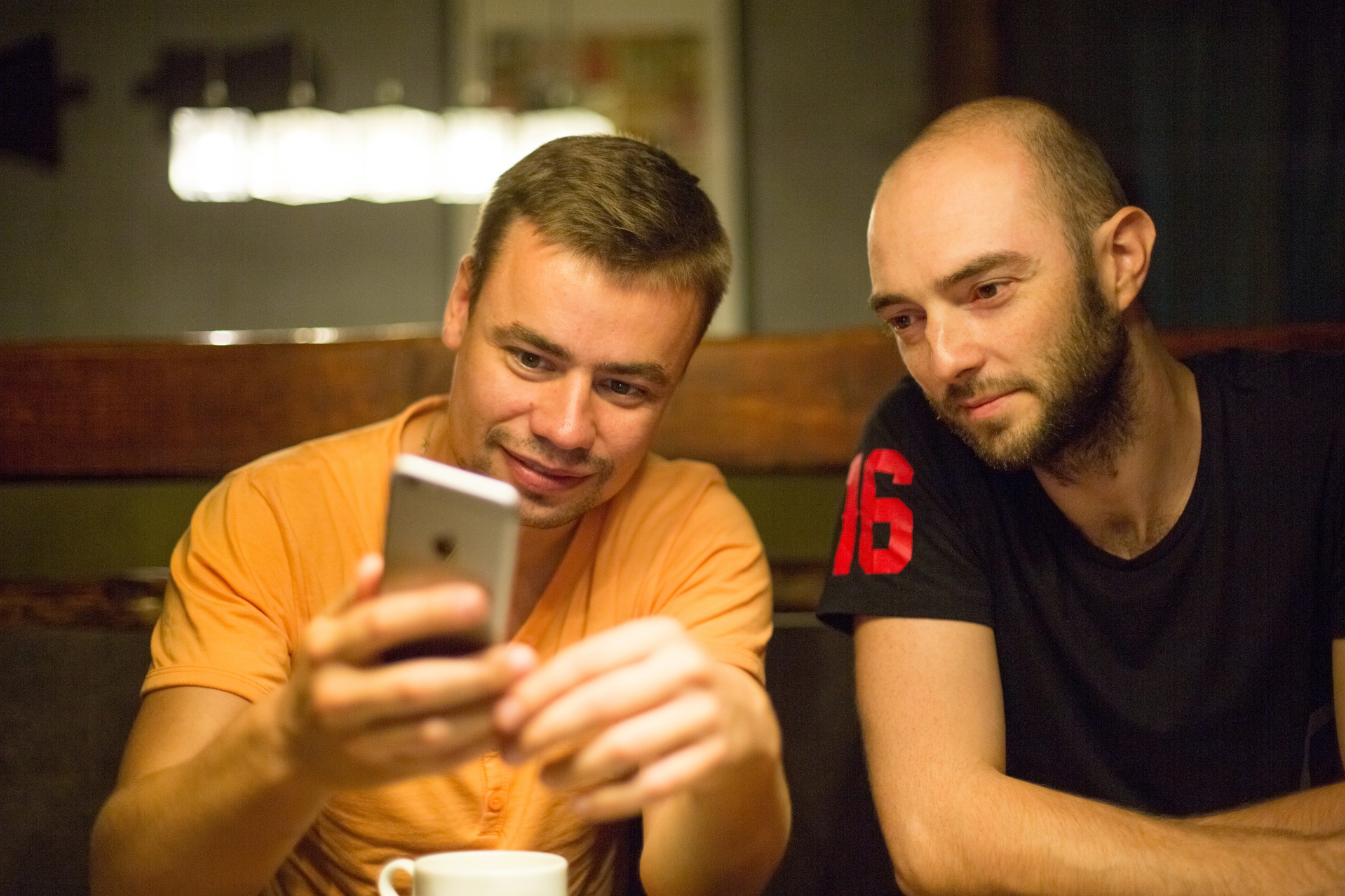 Two WordPress developers sitting at table exploring career opportunities with remap online on smartphone